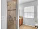 Bright bathroom featuring a tiled shower with glass door, vanity, and window at 618 Meadow Park Dr, Minneola, FL 34715