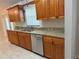 Traditional kitchen with wood cabinets, granite countertops, stainless steel appliances and neutral tiled floors at 618 Meadow Park Dr, Minneola, FL 34715