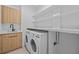 Well-equipped laundry room with modern washer, dryer, cabinets, sink and plenty of shelving space at 6427 Chorus Dr, Mascotte, FL 34753