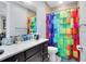 Well-lit bathroom with colorful shower curtain, dark vanity and a white marble countertop at 7873 Dausset St, Orlando, FL 32827