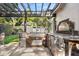 Outdoor kitchen with stainless steel appliances, stone counters, and a pergola for shade creates an inviting space at 100 Kennison Dr, Orlando, FL 32801