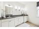Bathroom featuring double sinks with granite countertops, white cabinetry and a window for natural lighting at 101 W Oakland Ave, Oakland, FL 34760