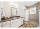 Bright bathroom featuring granite countertops, white cabinetry, and a tiled walk-in shower with glass door at 101 W Oakland Ave, Oakland, FL 34760