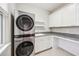 Laundry room with a modern washer and dryer unit, storage cabinets, and granite countertop at 101 W Oakland Ave, Oakland, FL 34760