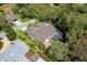 Overhead view of the property featuring a single-story home with a screened pool, lush landscaping, and mature trees at 1024 Destin Dr, Lake Wales, FL 33898