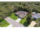 Aerial view of the property displaying a single-story home with a screened in pool area, spacious green lawn, and mature trees at 1024 Destin Dr, Lake Wales, FL 33898