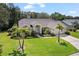 Charming single-story house with a well-maintained lawn, mature palm trees, and colorful landscaping at 1024 Destin Dr, Lake Wales, FL 33898
