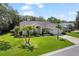 Beautiful single-story home featuring a lush, green lawn, mature palm trees, and a well-manicured garden landscape at 1024 Destin Dr, Lake Wales, FL 33898