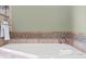 Closeup of large soaking tub with stone surround and decorative tile at 103 Greenleaf Ln, Altamonte Springs, FL 32714
