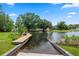 View of a concrete boat ramp and wood dock leading to a picturesque lake surrounded by lush greenery and trees at 103 Greenleaf Ln, Altamonte Springs, FL 32714