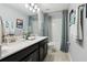 Bright bathroom featuring double sinks, modern fixtures, and a shower with blue curtains at 1082 Trappers Trail Loop, Davenport, FL 33896