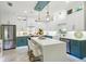 A newly renovated kitchen boasts bright white cabinetry with blue accents, a center island, stainless steel appliances, and tile flooring at 1082 Trappers Trail Loop, Davenport, FL 33896