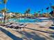 Inviting community pool with lounge chairs, mature palms, and nearby residential buildings at 1082 Trappers Trail Loop, Davenport, FL 33896