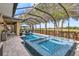 A screened-in pool area with a hot tub, outdoor seating, and views of the golf course at 1082 Trappers Trail Loop, Davenport, FL 33896