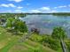 Aerial view shows a dock and boathouse nestled by a lake with lush green lawn, trees, and clear blue sky at 13120 Zori Ln, Windermere, FL 34786