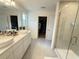 Modern bathroom with double sinks, tile floors, glass-enclosed shower, and walk-in closet at 14533 Crestavista Ave, Clermont, FL 34714