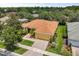 Aerial view of the home featuring a well-manicured lawn, colorful landscaping, and a brick paved driveway at 187 Tall Pines Pass, Kissimmee, FL 34759
