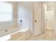 Bright bathroom featuring a tub under a window and a doorway to a shower with white tile at 2320 Red Ember Rd, Oviedo, FL 32765