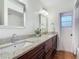 Bathroom featuring dual sinks with granite countertops, dark wood cabinets, and a large mirror at 2350 Worthington Rd, Maitland, FL 32751