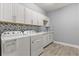 Bright laundry room with ample cabinet space, blue decorative tile backsplash, and modern washer and dryer at 2431 Knoll Dr, Apopka, FL 32712