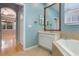 Light filled bathroom featuring a soaking tub, vanity with framed mirror, and blue painted walls at 3436 Gerber Daisy Ln, Oviedo, FL 32766