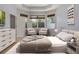 Bright bedroom featuring a tray ceiling, two chairs with decor and abundant natural light from three windows at 3436 Gerber Daisy Ln, Oviedo, FL 32766
