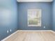 Bedroom with blue painted walls, laminate flooring, base molding, and a window to the outside at 3436 Gerber Daisy Ln, Oviedo, FL 32766