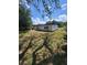 Shows backyard with grass with a white house, black roof, and trees in the background at 3463 Fekany Pl, Orlando, FL 32805