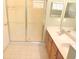 Well-lit bathroom featuring a double sink vanity, mirror, and glass-enclosed shower at 402 Ravenshill Way, Deland, FL 32724