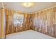 Simple bedroom with wood-look walls, white carpet, and a window with decorative curtains at 4279 Bomber Rd, Bartow, FL 33830