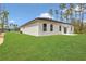 Rear exterior of the home showcasing a manicured lawn, white stucco, black trim, and a lush landscape at 4364 Sw 172Nd Street Rd, Ocala, FL 34473