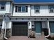 Charming townhouse showcasing a gray garage door, a light blue front door, and stone accents on the lower portion of the facade at 5113 Prairie Preserve Run, St Cloud, FL 34772