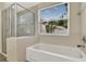 Bright bathroom featuring a tiled bathtub, a glass enclosed shower, and a window with outdoor views at 80 White Marsh Cir, Orlando, FL 32824