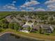 An aerial of a community with houses surrounding a lake, highlighting the house with a pool and a screen enclosure at 10142 Hidden Dunes Ln, Orlando, FL 32832