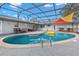 Sparkling pool in a screened-in lanai, surrounded by seating, cornhole, and an outdoor kitchen at 105 Spring Cove Trl, Altamonte Springs, FL 32714