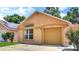 Charming one-story home with tan stucco, arched window, tan garage door, and manicured landscaping at 107 Pamala Ct, Sanford, FL 32771