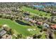 Aerial view showcasing lush golf course, beautiful homes, mature trees, and ponds in a neighborhood at 11415 N Camden Commons Dr, Windermere, FL 34786