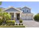 Charming two-story home featuring a well-manicured lawn and a covered front porch with stone supports and a two car garage at 11993 Charades St, Orlando, FL 32832