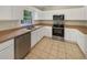 Well-lit kitchen with white cabinets, stainless steel appliances, ample counter space, and tile flooring for easy maintenance at 131 Pecan Pass, Ocala, FL 34472