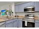 Close-up of a kitchen with granite countertops, stainless steel appliances, and blue cabinets at 13415 Blue Heron Beach Dr # 409, Orlando, FL 32821