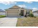 Charming single-story home with a well-maintained lawn, concrete driveway, and attached two-car garage at 140 Highland Meadows St, Davenport, FL 33837