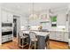 Bright kitchen features white cabinets, gray island with seating, stainless steel appliances, and a marble backsplash at 141 S Phelps Ave, Winter Park, FL 32789