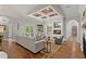 Living room with coffered ceiling, fireplace with mounted TV, hardwood floors, and access to outdoor patio at 141 S Phelps Ave, Winter Park, FL 32789
