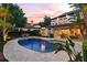 Outdoor pool area with patio and lounge chairs; home's exterior and tropical landscaping at dusk at 141 S Phelps Ave, Winter Park, FL 32789