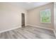 Neutral bedroom with grey laminate flooring, a window, and a door to the closet at 14244 Walcott Ave, Orlando, FL 32827