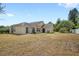 Expansive backyard showing the exterior of the home with sliding glass doors and drought tolerant landscaping at 144 Henue Ct, Davenport, FL 33896