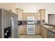 Functional kitchen with stainless steel appliances, light wood cabinetry, and tile flooring at 144 Henue Ct, Davenport, FL 33896