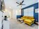 Cozy living room with a yellow sofa, blue accent wall and ceiling fan at 15959 Pantuso Aly, Winter Garden, FL 34787