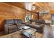 Inviting living room with wood-paneled walls, comfortable sofas, and a glass coffee table, creating a warm and cozy atmosphere at 1650 Old Eustis Rd, Mount Dora, FL 32757