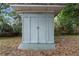 Light blue storage shed on a concrete platform, surrounded by lush greenery and foliage at 1650 Old Eustis Rd, Mount Dora, FL 32757
